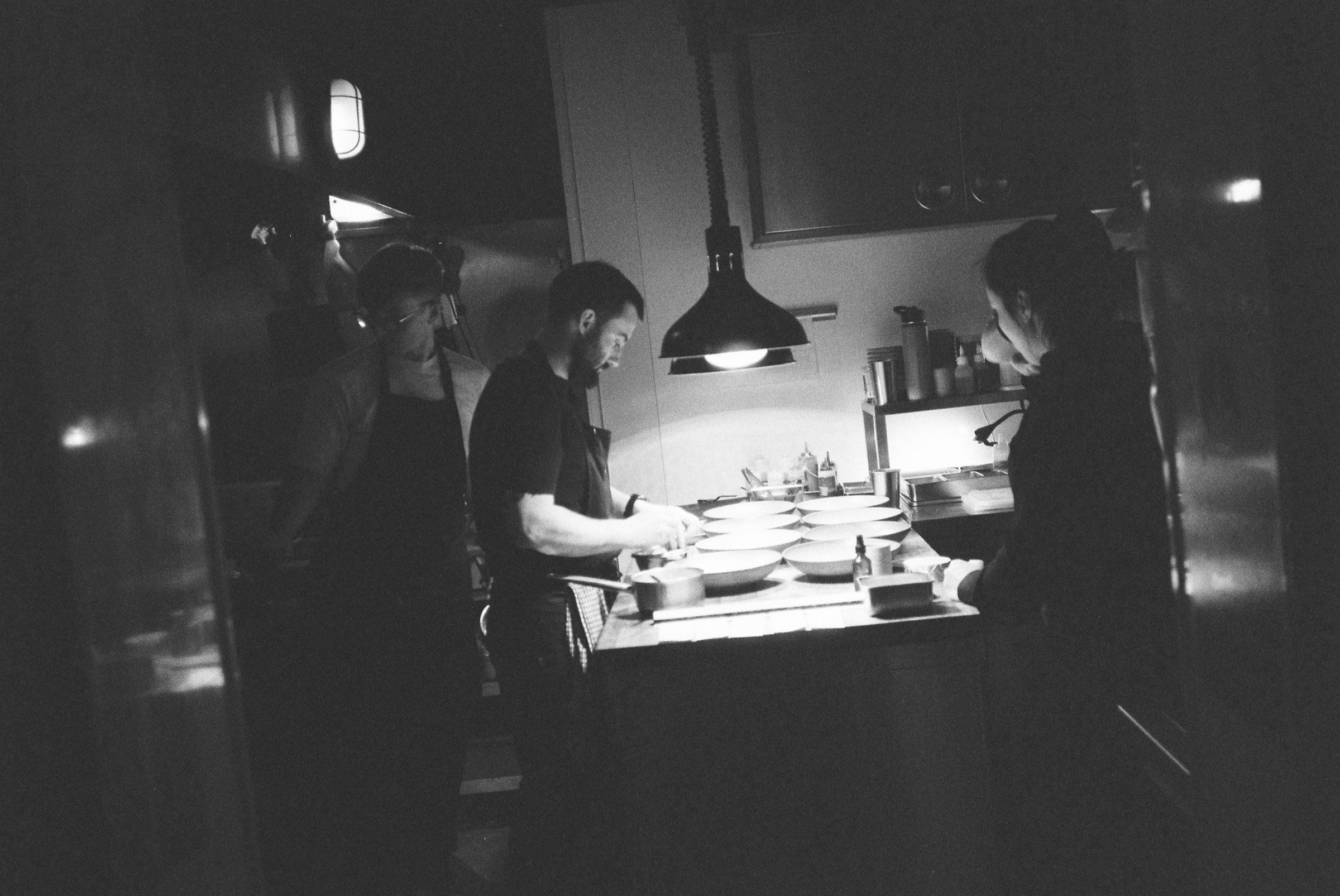 The Cardinal kitchen team plating at the pass, in black and white